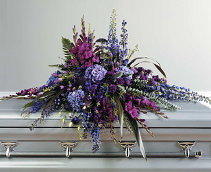 Mixed casket spray of mixed purple flowers from Bunn Flowers & Gifts, local florist in Pittsburg, TX